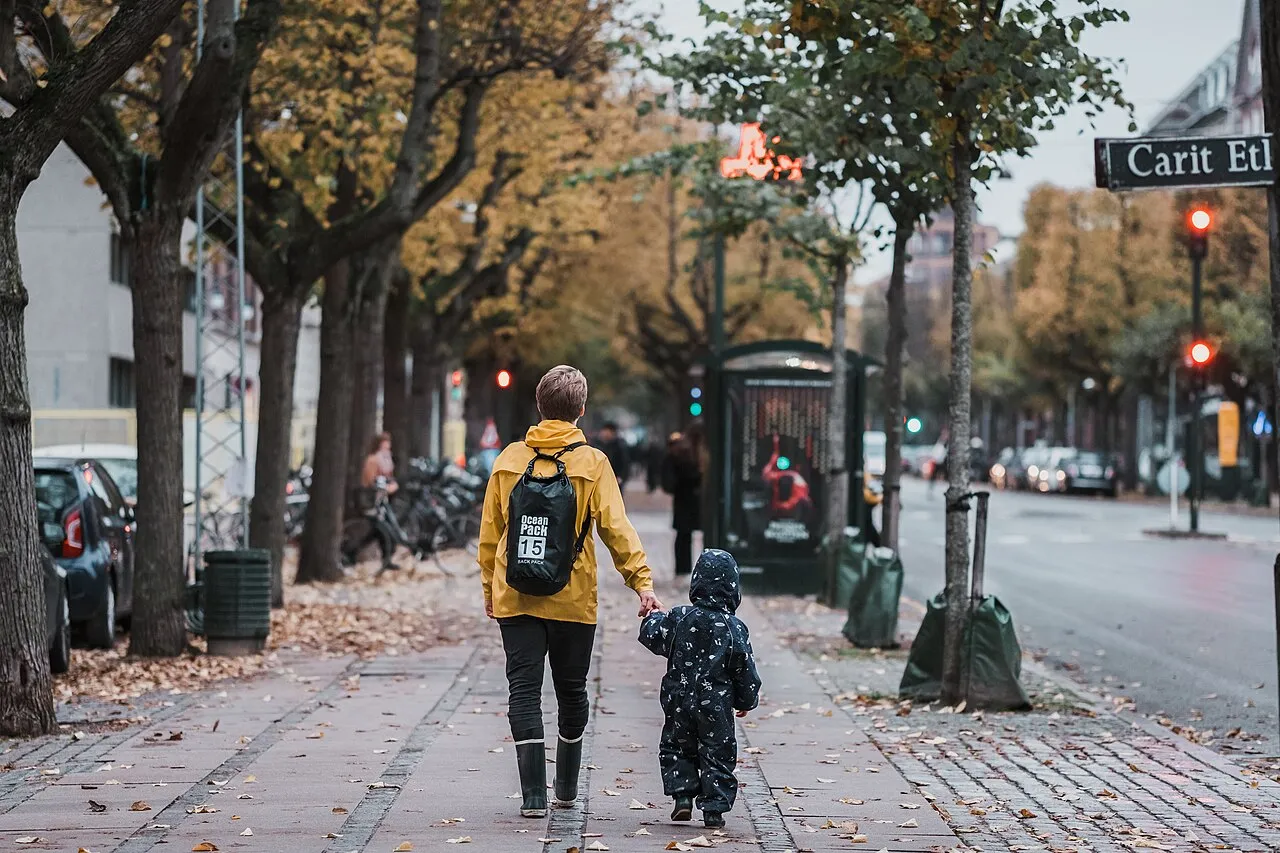 Een vader en zoon lopen over een bomenlaan in Denemarken tijdens herfstweer.